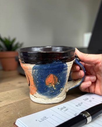 Handmade ceramic mug held in hand, showing scale and comfortable grip