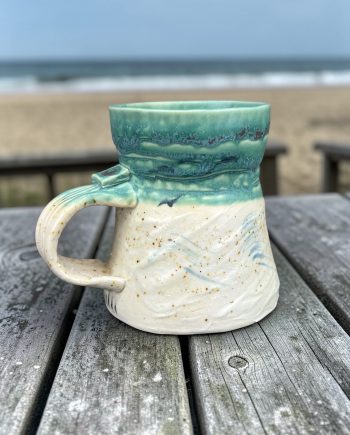 Handmade ceramic mug with green glaze and white textured base inspired by shoreline movement