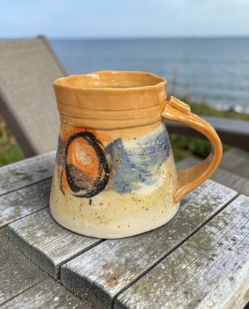 Handmade Lake Michigan ceramic mug with warm sun tones, shifting blue shoreline movement, and sand-textured surface. One of a kind.