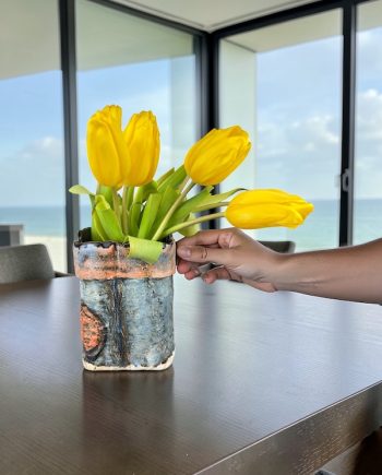 Lake Michigan ceramic vase with bird track texture and blue shoreline glaze with someone adjusting tulips