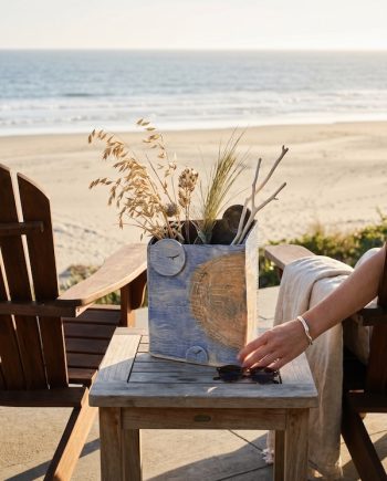 Handbuilt porcelain Lake Michigan vase featuring the sun, moon, seagull footprints, and shoreline textures displayed with dried grasses overlooking the beach.
